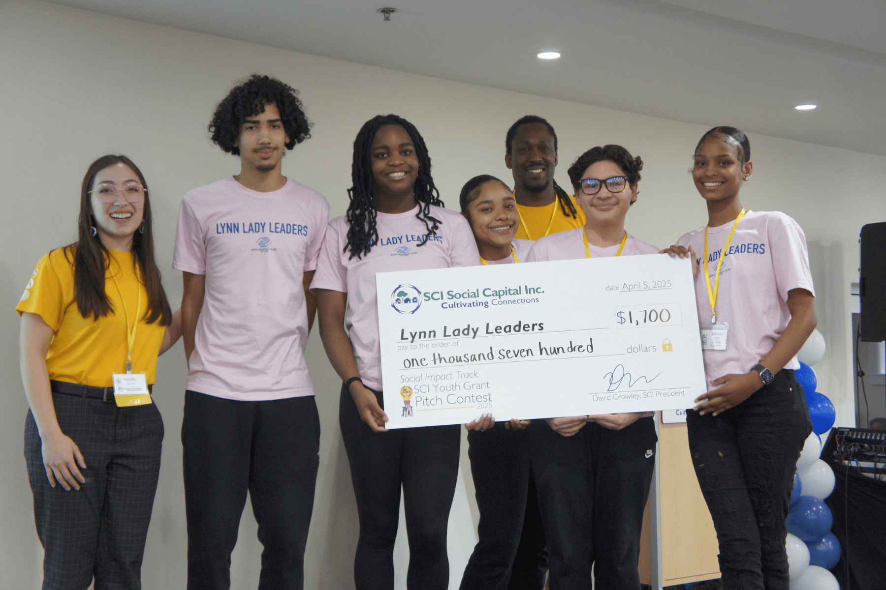 Divine Egbuta (center) poses with fellow youth teammates at the 2025 Pitch Event for SCI’s Youth Grant Pitch Contest along with SCI Program Manager, Nicole Osborne (left), and SCI Managing Director, Philip Gordon (background).