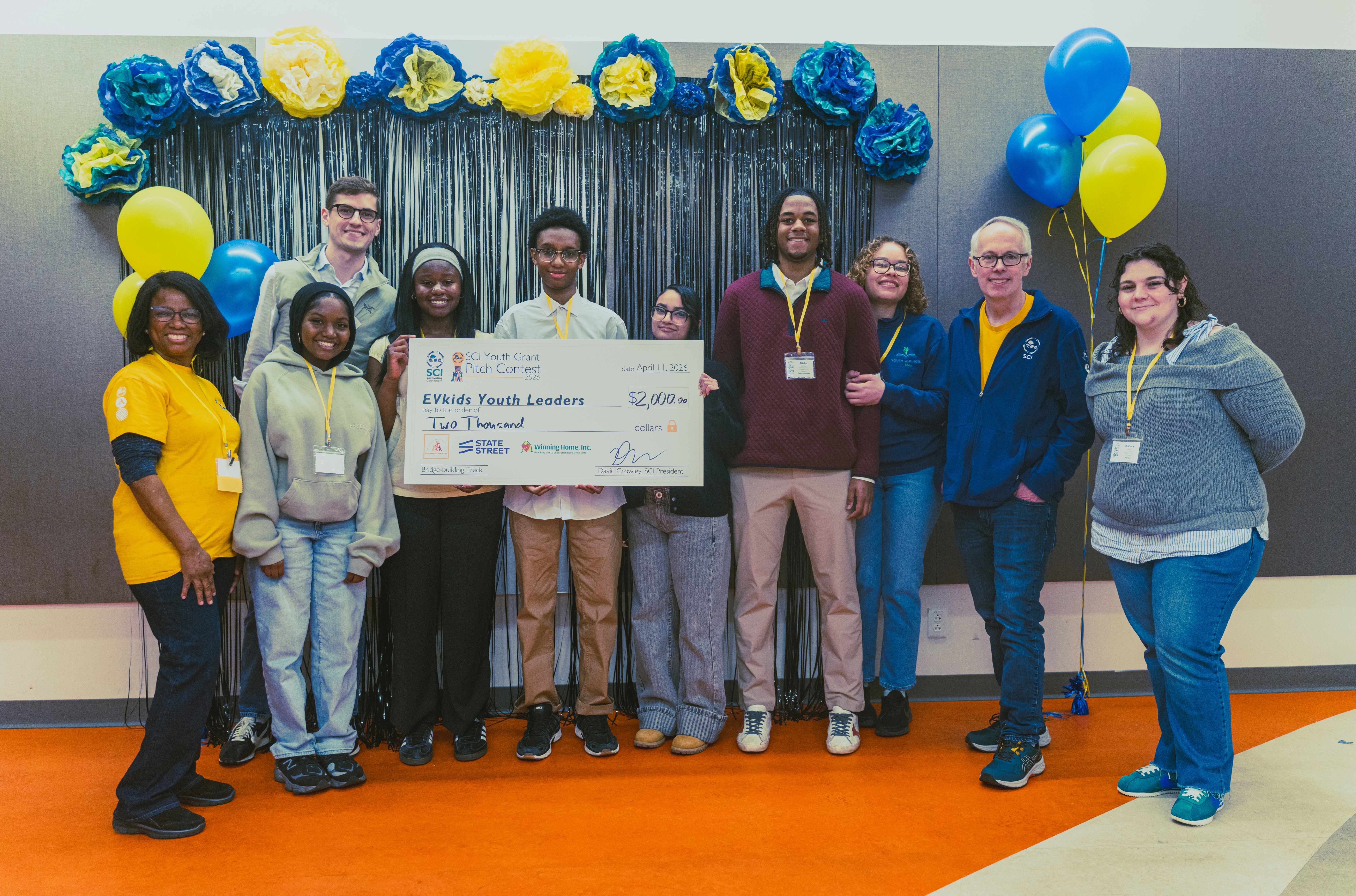 EVkids Youth Leaders (second from left to right), Alexa Santana, Mariama Bangoura, Blake Dacosta, Fatoumata Balde, and Souleymane Diallo pose with Team Advisors, Dede Evans (third from right) and Ashley Clavel (right); Pitch Coach, Sam Gerry (background, left); SCI Program Coordinator, Vitalie Memeus (left); and SCI President, David Crowley (second from right).